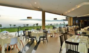 a restaurant with white tables and chairs with a view at EPIC Hotel & Suites in Nyagatare