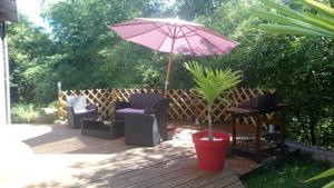 a patio with a pink umbrella and chairs and a plant at Les Bambous in Petite Île
