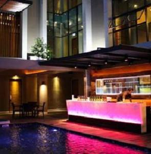 曼谷的住宿－暹羅思瓦納酒店，一座带游泳池的建筑和一座带紫色照明的酒吧