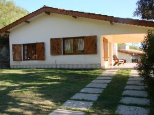 ein kleines weißes Haus mit einer Bank im Hof in der Unterkunft Cabañas El Tirol in La Falda