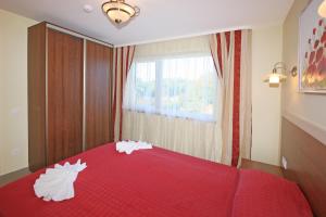 a bedroom with a red bed with two pillows on it at Vila Medus in Palanga