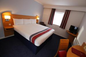 a hotel room with a bed and a television at Ramada Wakefield in Wakefield