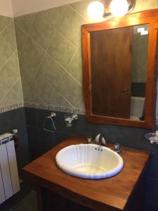 La salle de bains est pourvue d'un lavabo blanc et d'un miroir. dans l'établissement Cabañas El Tirol, à La Falda