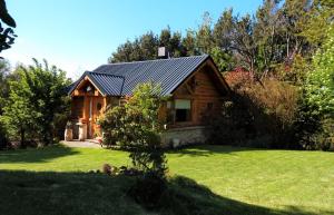 una cabaña de madera en un patio con césped verde en Blue Bird House en San Carlos de Bariloche