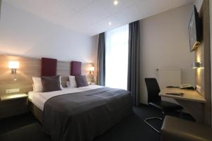 a hotel room with a bed and a desk and a window at Hotel Hohenstaufen in Koblenz