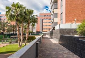 una pasarela frente a un edificio con palmeras en EnjoyGranada EMIR 3F - POOL, GYM & Free Parking en Granada