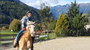 a woman riding on a horse in the mountains at Bio-Bauernhof Auernig in Obervellach