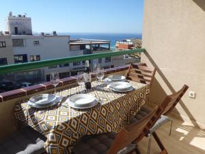 una mesa con platos y copas de vino en el balcón en Clara's sun apt en Morro del Jable
