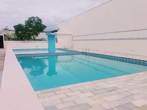 a swimming pool with blue water in front of a building at Apto Praia Bertioga - 3 dormitorios sendo uma suite in Bertioga