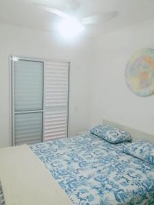 a bedroom with a bed with a blue comforter at Apto Praia Bertioga - 3 dormitorios sendo uma suite in Bertioga +31 photos