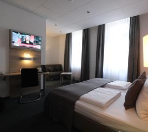 a hotel room with a bed and a desk and a tv at Hotel Hohenstaufen in Koblenz