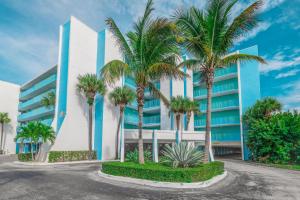a building with palm trees in front of it at Turtle Reef Club by Capital Vacations in Jensen Beach