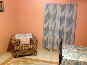 a living room with a chair and a bed at Eddie's Night Rest in Lucea