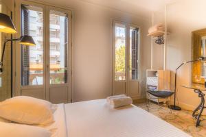 een slaapkamer met een bed, een bureau en 2 ramen bij Habitació amb encant in Sitges