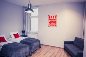 ein Zimmer mit 2 Betten und einem Sofa und einem Schild in der Unterkunft Apartamenty 21 Basic in Stettin