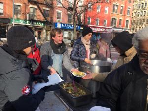 un grupo de personas comiendo comida en una calle de la ciudad en Interfaith Retreats, en Nueva York