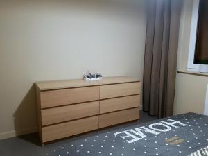 a wooden dresser in a bedroom with a bed at Nowoczesny Apartament w Centrum in Kościerzyna