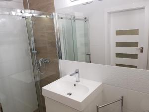 a white bathroom with a sink and a shower at Nowoczesny Apartament w Centrum in Kościerzyna