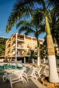 un complejo con piscina, palmeras y sillas en Hotel Costa Choco, en Bahía Solano