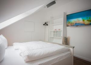 ein weißes Schlafzimmer mit einem Bett und einem Flachbild-TV in der Unterkunft Welcome in - Am Bergelchen 58-J in Winterberg