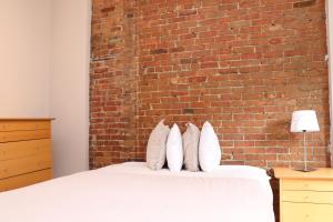 1 dormitorio con pared de ladrillo y cama con almohadas en Furnished Studio in the South End #4, en Boston