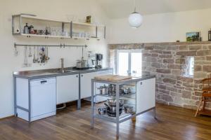 eine Küche mit weißen Schränken und einer Ziegelwand in der Unterkunft Nengshof Ferienwohnung Wildrose in Wißmannsdorf