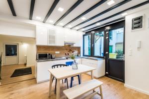 ブダペストにあるLuxury LOFT Apartments Budapestの白いキャビネット、テーブルと椅子付きのキッチンが備わります。