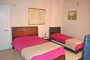two beds in a bedroom with pink and white sheets at Condominio Atlantis in Coveñas