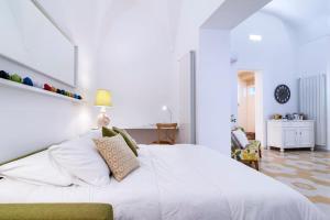 una camera con un grande letto bianco e una sedia di Li Frati Casa Vacanze a Lecce
