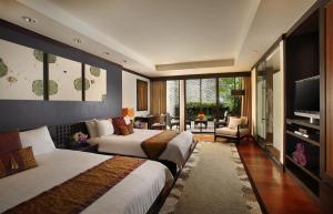 a hotel room with two beds and a television at Dusit Thani Laguna Phuket in Bang Tao Beach