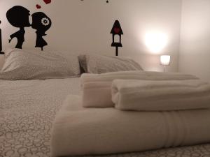 una camera da letto con letto, lenzuola e cuscini bianchi di mungiBEDdu Apartment a Catania