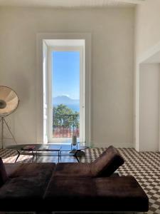 ein Wohnzimmer mit einem Sofa und einem großen Fenster in der Unterkunft PrimoPianoPosillipo in Neapel