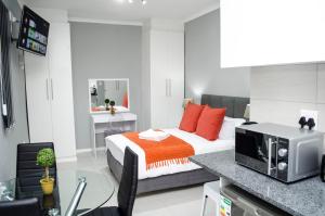 Cape Town Micro Apartments في كيب تاون: غرفة نوم مع سرير مع وسائد برتقالية وميكروويف
