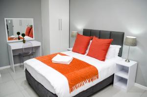 1 dormitorio con 1 cama grande con almohadas rojas y espejo en Cape Town Micro Apartments, en Ciudad del Cabo