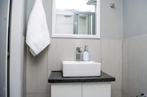 a bathroom with a white sink and a mirror at Cape Town Micro Apartments in Cape Town