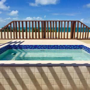 a swimming pool with a wooden fence and the ocean at Caye Reef Condos in Caye Caulker