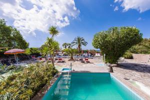 a swimming pool with a beach and palm trees at Hotel La Mandorla in Ischia