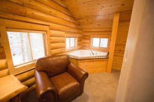 Habitación con bañera y silla en una cabaña de madera. en The Pines at Island Park, en Island Park