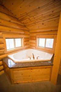 bañera grande en una cabaña de madera con ventana en The Pines at Island Park, en Island Park