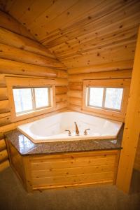 eine große Badewanne in einem Blockhaus mit einem Fenster in der Unterkunft The Pines at Island Park in Island Park + 37 Fotos