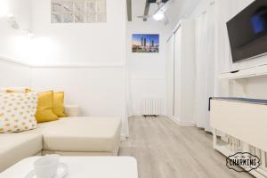 a white living room with a couch and a tv at Charming Puerta de Toledo II in Madrid