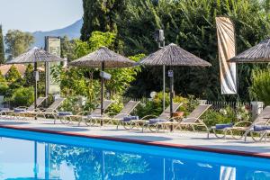 a group of chairs and umbrellas next to a swimming pool at Silver Bay Hotel Kontokali Corfu in Kontokali