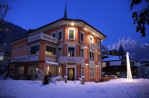 a large building with a christmas tree in the snow at Hotel Luis in Fiera di Primiero