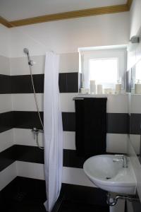 a black and white bathroom with a sink and a shower at Sunset Apartments in Hajdúszoboszló