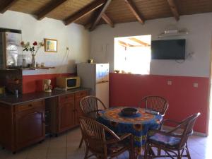 cocina con mesa, sillas y nevera en Chez sidoine Meublé 2 chambres, en Le Moule