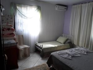 Habitación pequeña con 2 camas y ventana en Roseli's Vacation Home, en Gramado