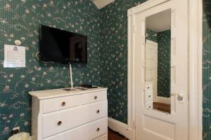 a bedroom with a dresser and a tv on a wall at The Coolidge Corner Guest House: A Brookline Bed and Breakfast in Brookline
