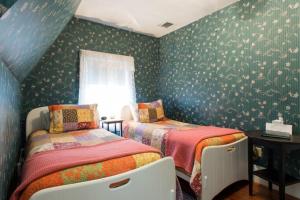 2 camas en un dormitorio con paredes verdes y flores en The Coolidge Corner Guest House: A Brookline Bed and Breakfast en Brookline