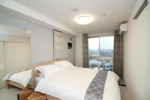 a bedroom with a white bed and a window at W&M House in Kanazawa