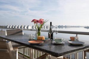 a table with a bottle of wine and a vase of flowers at Haus Hafenblick in Olpenitz